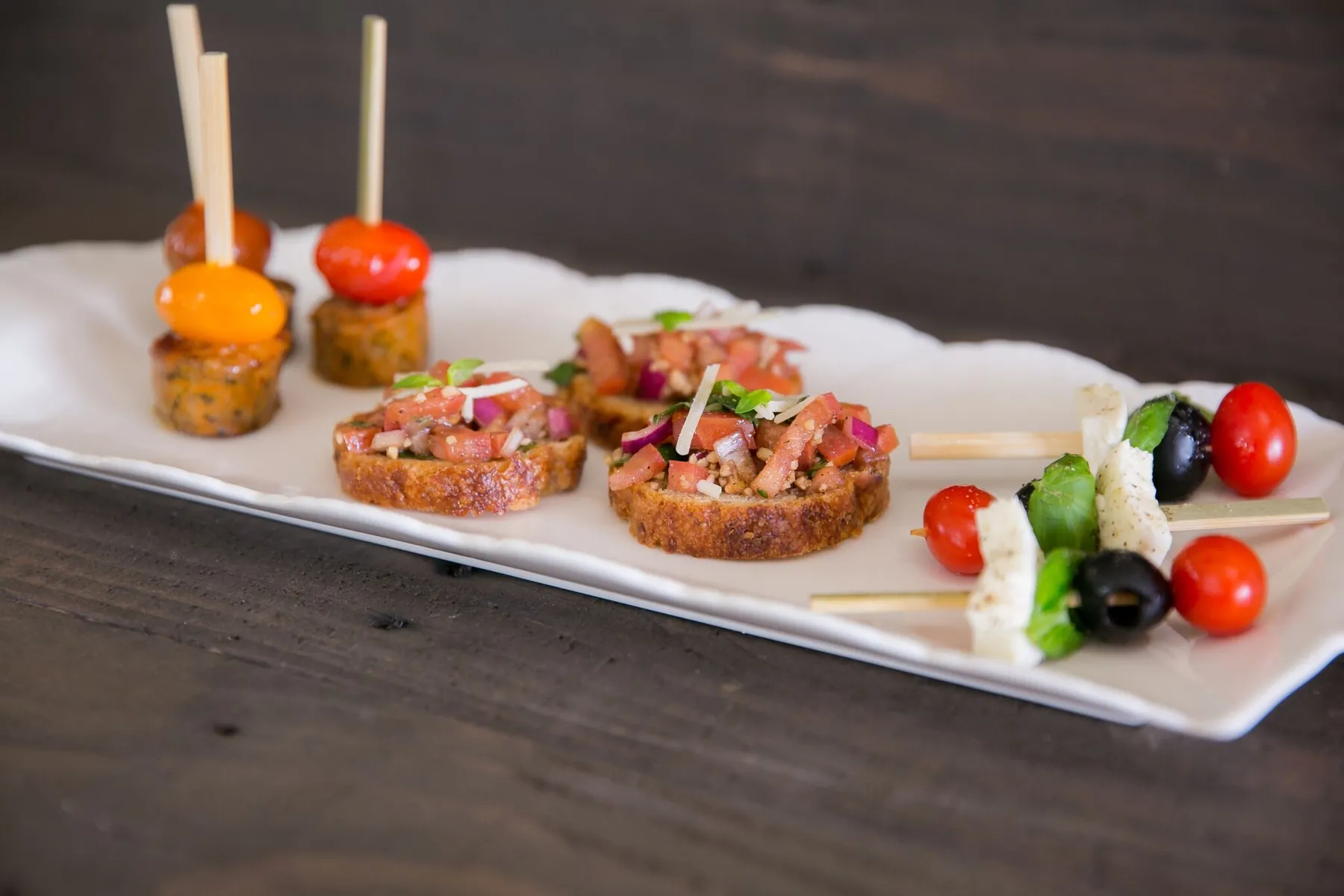 Appetizer platter with bruschetta, caprese kabobs and chicken sausage kabobs